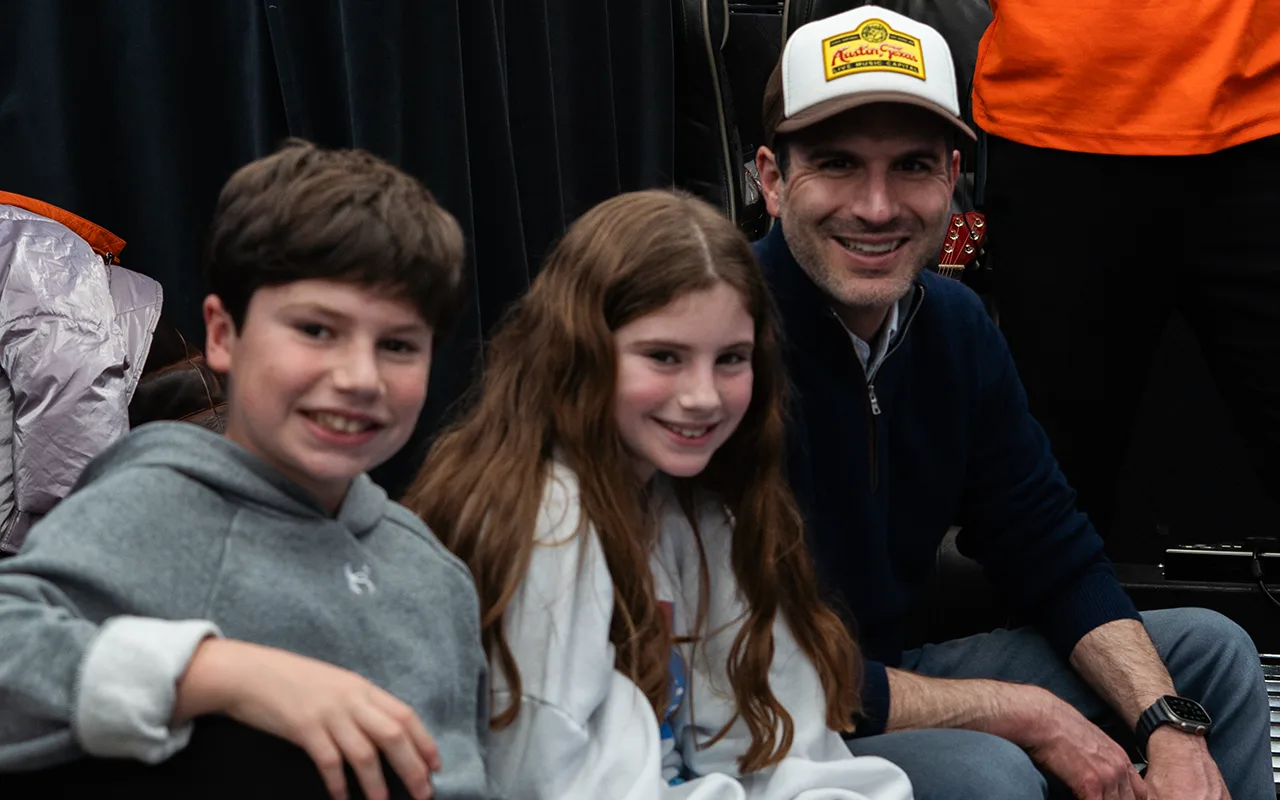 Two children and their dad smiling on the bus