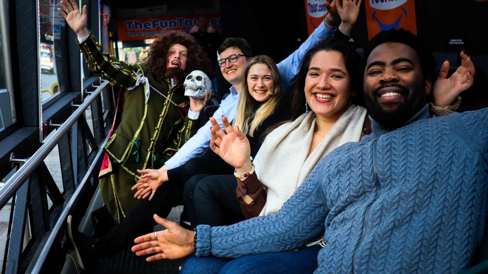Shakespeare character holding a skull with a laughing group of guests